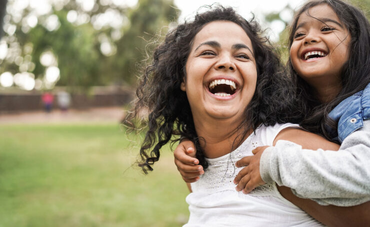 Woman and daughter laughing in park together